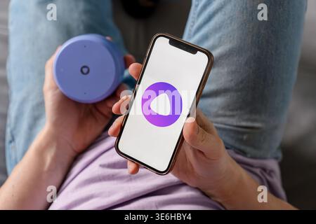 A man holds a smartphone with the Yandex Alice AI app and adjusts the Alice speaker. Saint Petersburg, Russia - 7 Apr 2026 Stock Photo
