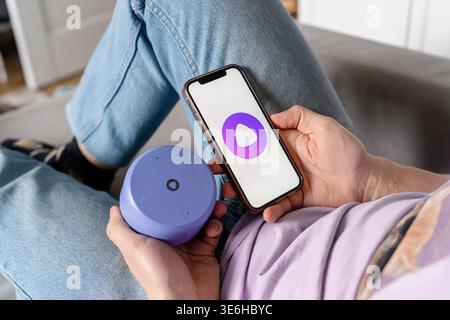 A man holds a smartphone with the Yandex Alice AI app and adjusts the Alice speaker. Saint Petersburg, Russia - 7 Apr 2026 Stock Photo