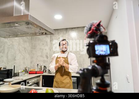 Chef vlogger recording a culinary tutorial video for social media, sharing recipes and food content in a kitchen Stock Photo