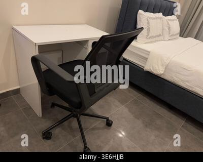 Home office setup with black chair at white desk in modern bedroom, suitable as a background. Mobile photo Stock Photo