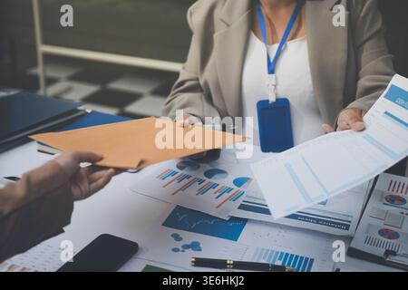 Business colleagues analyzing financial charts and reports on the table while having a focused discussion about strategies and market performance duri Stock Photo