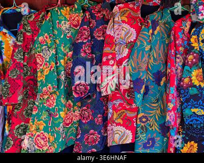 Vibrant traditional Chinese quilted floral jackets known as Dong Bei Da Hua on display in Dali Market, Yunnan, China. Stock Photo