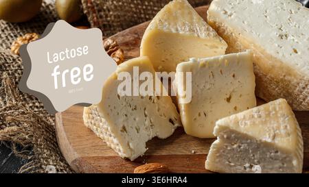Lactose free cheese displayed on a wooden board with nuts and burlap in the background Stock Photo