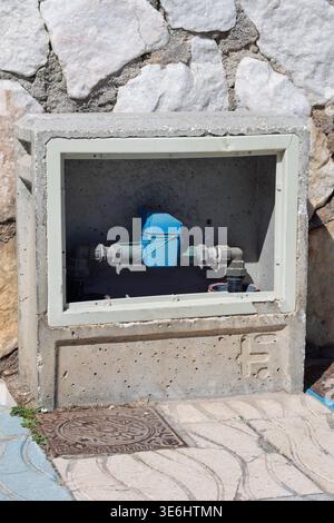 Water meter installed in a concrete cabinet measuring residential water consumption Stock Photo