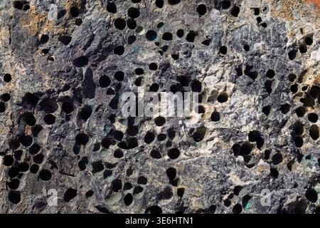 Basalt rock surface creating abstract pattern with dark hollows Stock Photo