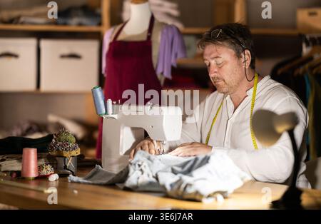 Middle-aged male dressmaker working with sewing-machine Stock Photo