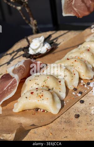 Close up of savory dumplings with thin slices of prosciutto ham on parchment paper. Appetizing food texture and detail. Stock Photo