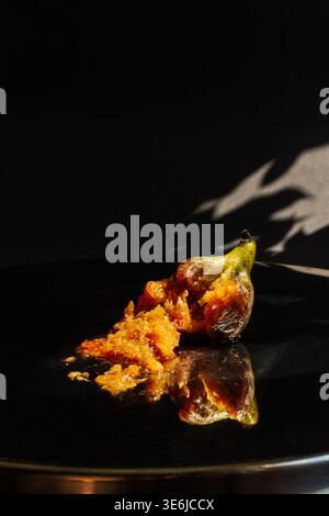 Dramatic still life of a cut ripe fig on a dark reflective surface. High contrast food art for luxury branding and editorial. Stock Photo