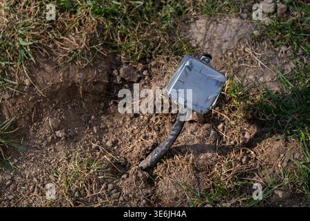 Close view of an exposed electrical junction box with cable emerging from soil in outdoor environment. Concept of electrical hazard, unsafe wiring, an Stock Photo