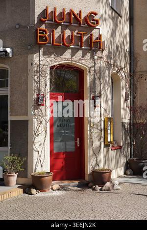 Berlin, Germany - April 7, 2026: Close-up of the red entrance door and vintage-style neon sign of the restaurant "Jungbluth" in Steglitz. Stock Photo