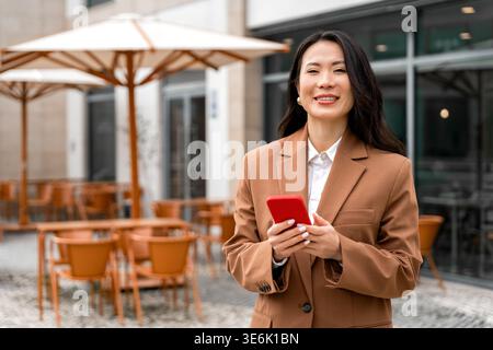 Smiling professional woman using smartphone at outdoor cafe Stock Photo