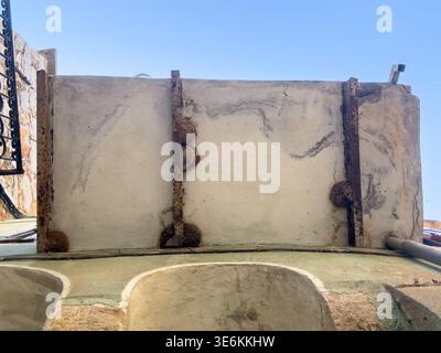 Low angle view of an aged balcony with rusted iron supports and cracked plaster wall in Olympoi village, Chios island, Greece. Stock Photo