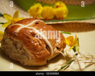 Easter hot cross bun with eggs and daffodil flowers yellow background Stock Photo