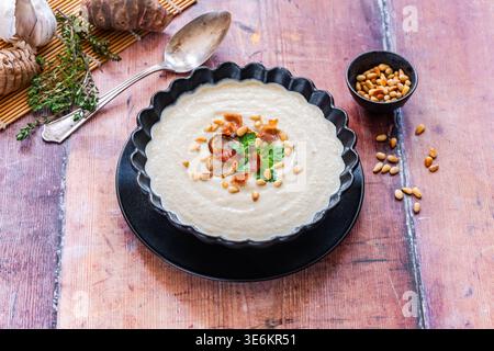 Roasted Jerusalem Artichoke soup with crispy parma ham and pine nuts garnish Stock Photo