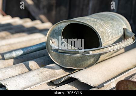 Rustic Metal Bucket Lying on Weathered Roof Tiles in Sunny Rural Farmhouse Setting Stock Photo