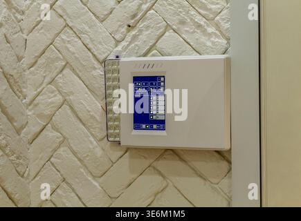 The image shows a security control panel mounted on a textured white wall. Stock Photo