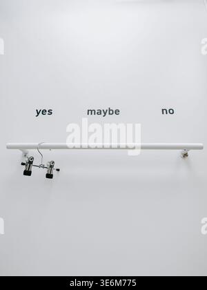 Riga, Latvia - April 4, 2026:Minimalist composition featuring “yes,” “maybe,” and “no” text above a horizontal bar with clips. Clean visual metaphor f Stock Photo