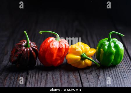 Habanero peppers arranged in line on wooden surface with dramatic light. Fresh chili assortment with rich colors natural texture Stock Photo