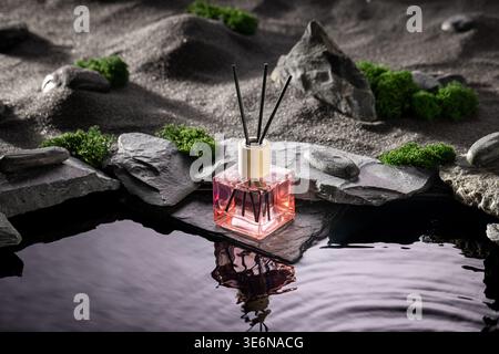Intense fragrance diffuser on a dark stone by the water. Fragrance diffuser on dark desert. Stock Photo