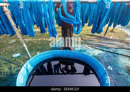 Brightly colored yarns and fabrics spread across open fields, drying under the sun—showcasing the beauty of traditional craftsmanship and vibrant text Stock Photo