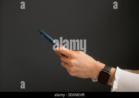A close-up image of the hands of an unidentified woman holding and using a smartphone, browsing the internet, checking social media, and using a mobil Stock Photo