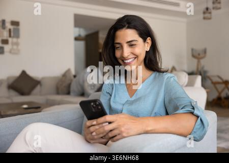 Woman smiling as reading message or watching content on smartphone Stock Photo