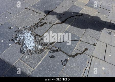 A pile of discarded ice cubes melting outdoors in the sun on a pavement, UK Stock Photo