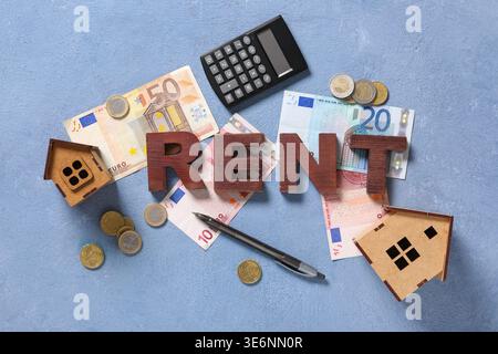 Word RENT with money, calculator and wooden houses on blue grunge background Stock Photo
