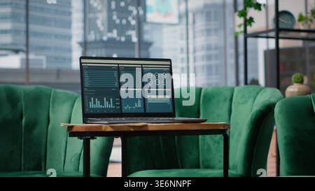 Big data reports and graphics showcasing business corporation success, empty luxurious office with a laptop on the table. Professional workspace with pc display running trends. Stock Photo