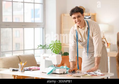 Young male tailor with sewing machine and tablet computer in atelier Stock Photo