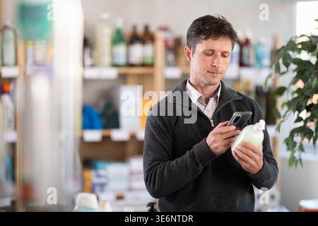 Middle-aged woman scanning QR-code on detergent at supermarket Stock Photo