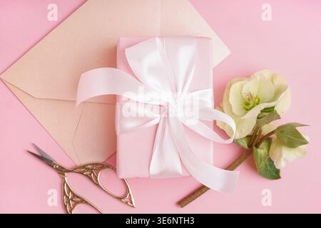 Gift box with beautiful flowers and envelope on pink background Stock Photo