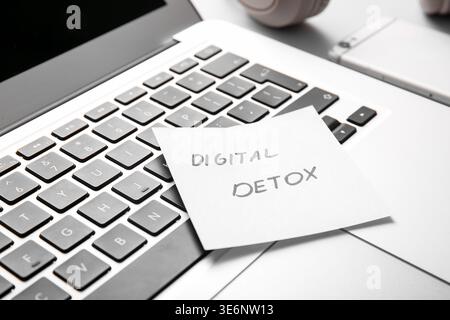 Sticky note with text DIGITAL DETOX and modern laptop, closeup Stock Photo