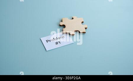 Single wooden puzzle piece next to paper labeled problem number one Stock Photo