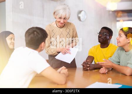 Elderly female tutor conducting foreign language speaking club Stock Photo