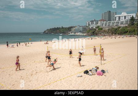 People playing beach volleyball on the sand at Bondi Beach with coastal buildings and the ocean in the background. Stock Photo