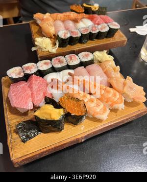 Assorted sushi, nigiri and maki rolls served on wooden trays in a restaurant in Tokyo, Japan. Stock Photo