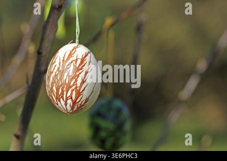 Branches with decorated Easter eggs outdoors, an egg in the foreground with brown decoration. Decorated in Horn-Bad Meinberg Stock Photo