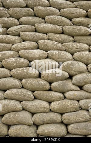 Sedimentary coastal cliffs protected by a stacked sandbag revetment installed to slow erosion from waves undercutting the base. The rounded shapes in Stock Photo
