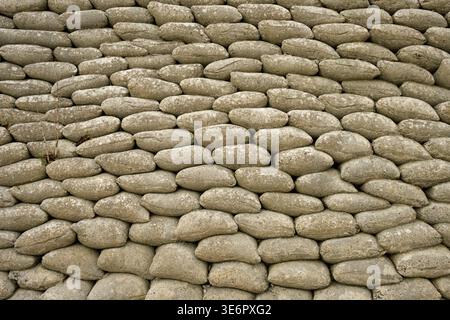Sedimentary coastal cliffs protected by a stacked sandbag revetment installed to slow erosion from waves undercutting the base. The rounded shapes in Stock Photo