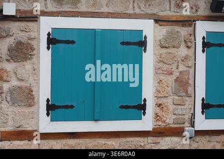 Bright blue shutters on a stone wall in a small town Stock Photo