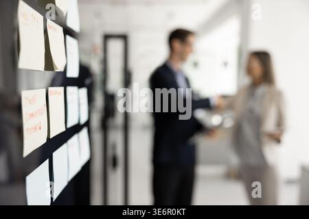 Close-up sticky notes on glass wall, filled with handwritten reminders Stock Photo