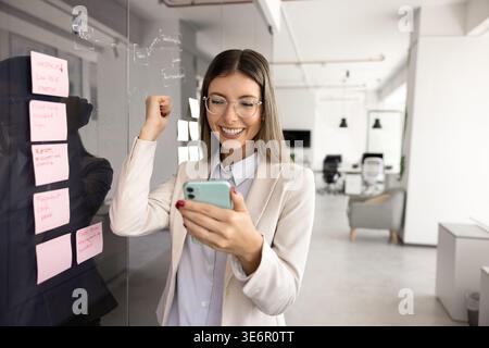 Happy professional woman reading great business news in sms Stock Photo