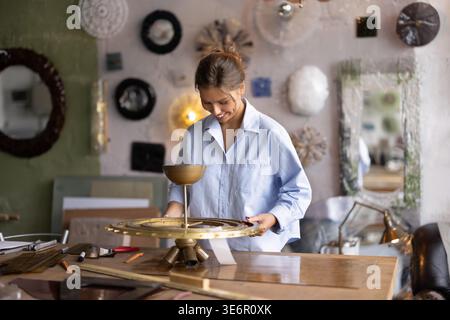 Artisan collecting parts of handcrafted sconce lamp in workshop Stock Photo