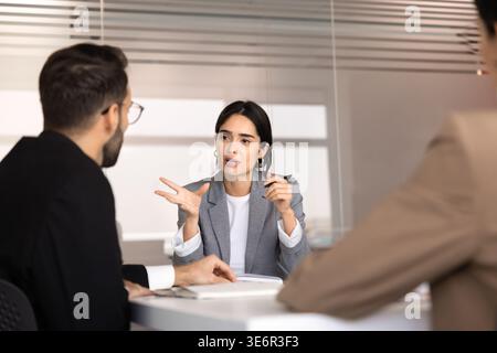 Professional woman consulting company clients, share information, planning strategy, explaining ideas and solutions with diverse team members during m Stock Photo