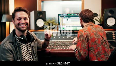 Music producer, team or man in studio with portrait, pride or experience in audio mixing. Collaboration, recording or sound engineers with confidence Stock Photo