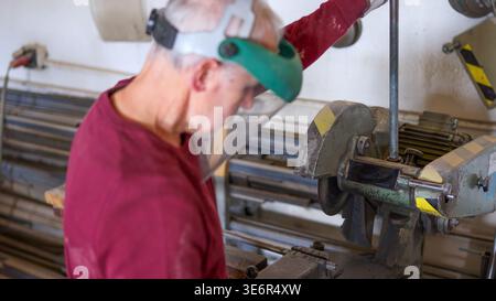 Worker shaping metal profile using cutting machine in workshop Stock Photo