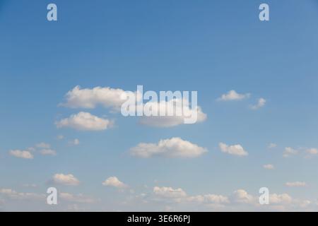 Many small white cumulus clouds scattered across a vast and clear blue sky. Stock Photo