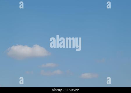 Small white wispy clouds scattered across a bright clear blue sky during the day. Stock Photo