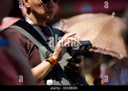 SAMUT SONGKHRAM, THAILAND-MAR 28, 2026: Male tourist using camera recording video, traveler exploring outdoor market, close up, Mae Klong. Stock Photo